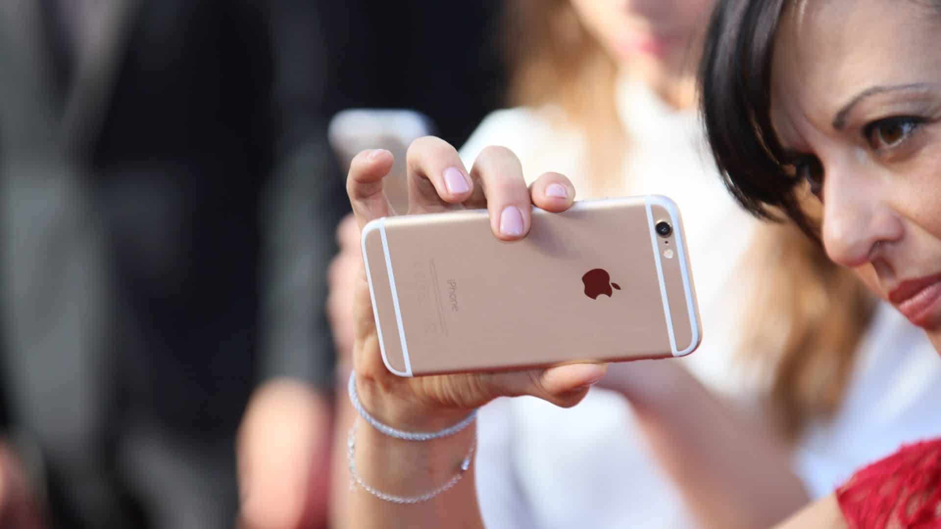 Mulher segurando iPhone na horizontal com apenas uma mão