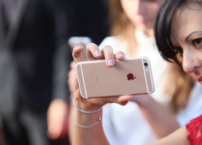 Mulher segurando iPhone na horizontal com apenas uma mão