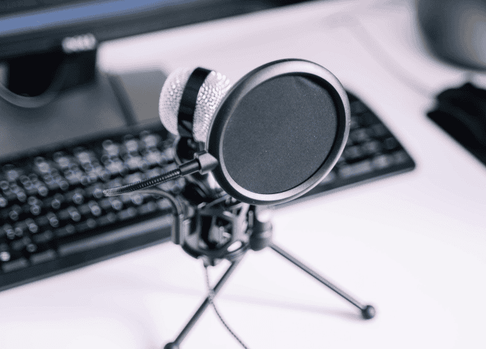imagem mostra um microfone posicionado em um tripé e conectado a um computador desktop