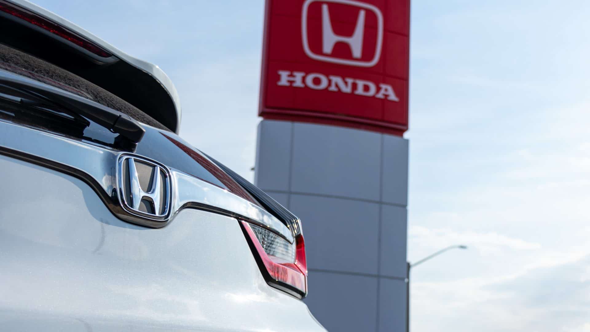 Traseira de um carro da Honda ornando com a fachada de uma concessionária da montadora