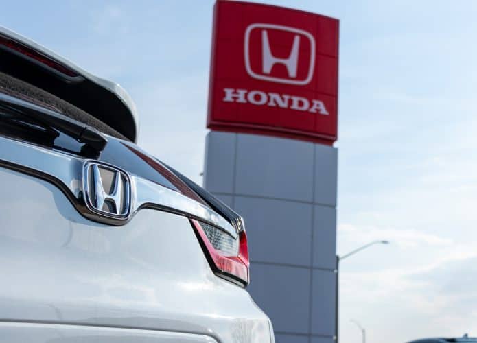 Traseira de um carro da Honda ornando com a fachada de uma concessionária da montadora