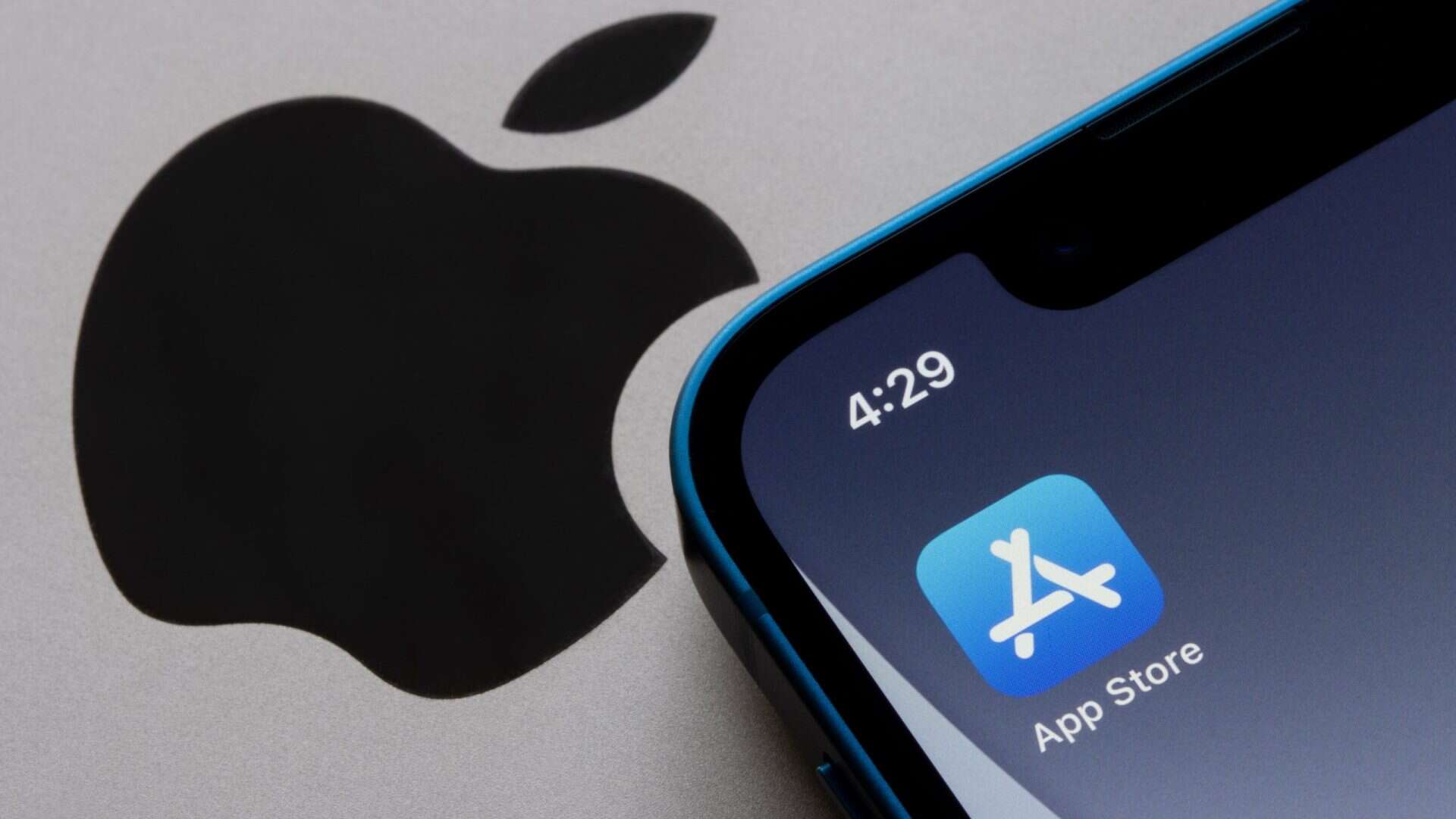 Ícone da App Store na tela inicial de um iPhone colocado ao lado de logotipo da marca em aparelho