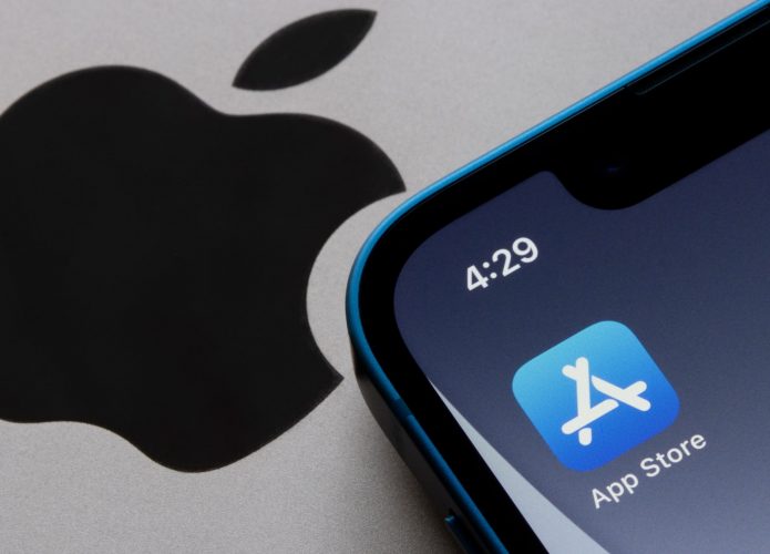 Ícone da App Store na tela inicial de um iPhone colocado ao lado de logotipo da marca em aparelho