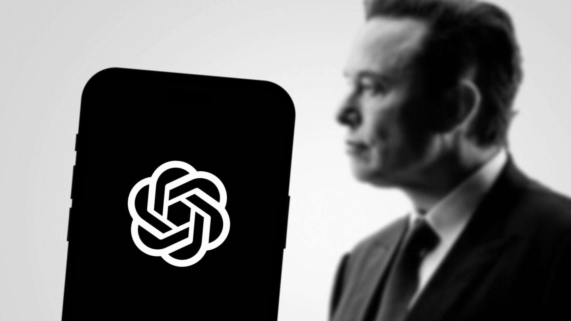 elon musk com o logo da OpenAI em um celular