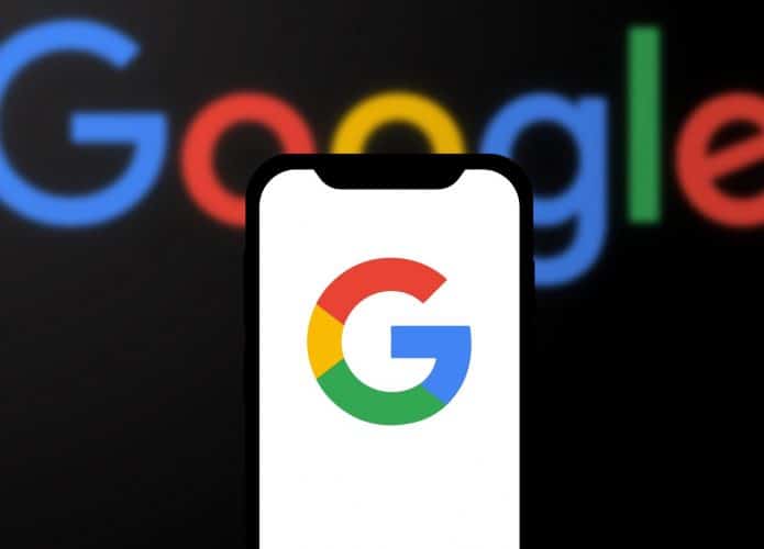 Logo do Google ao fundo e, à frente, em uma tela de smartphone, a letra G do logo da empresa
