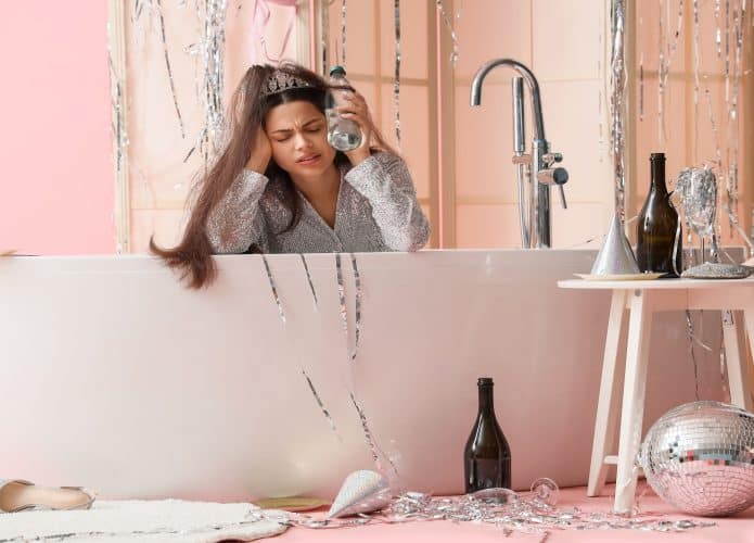 Mulher bêbada sofrendo de ressaca na banheira sobre fundo rosa