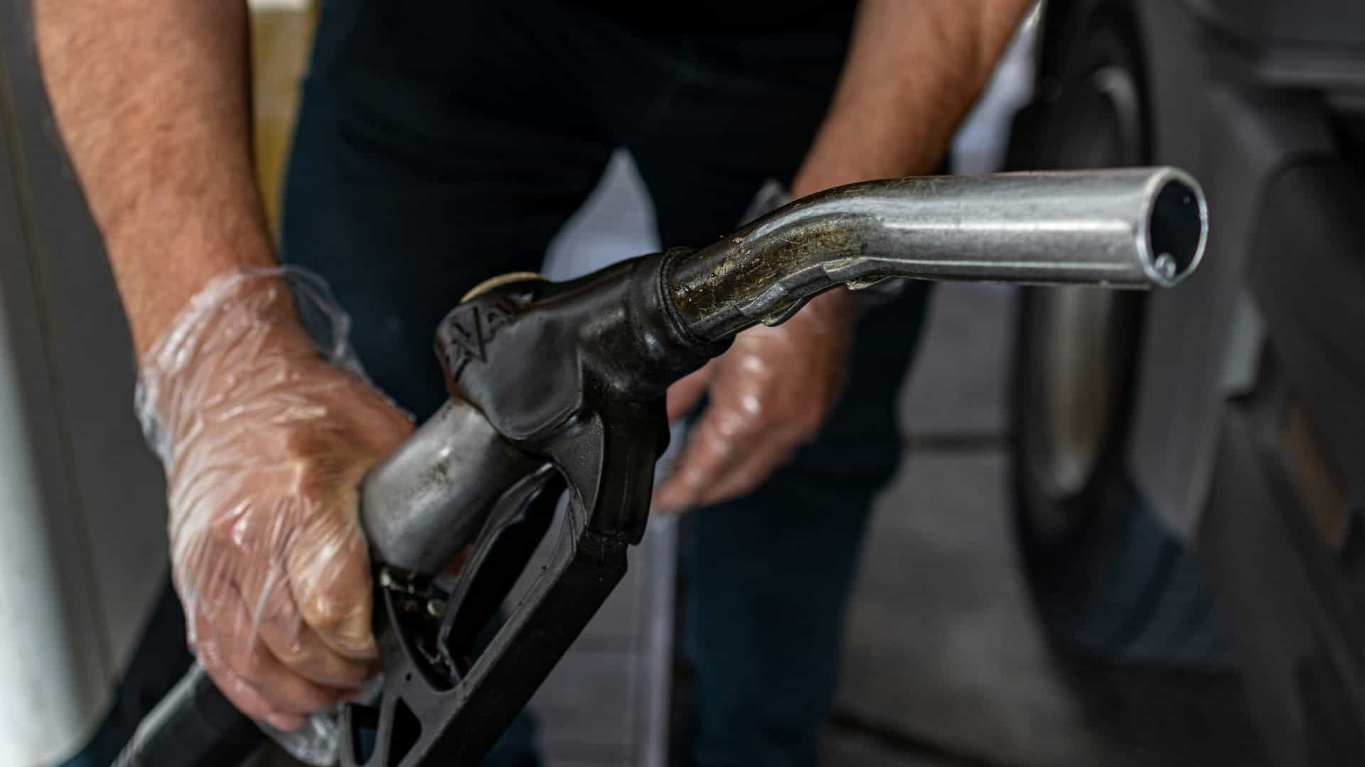 imagem mostra um frentista segurando o equipamento para abastecer o carro de uma pessoa no posto
