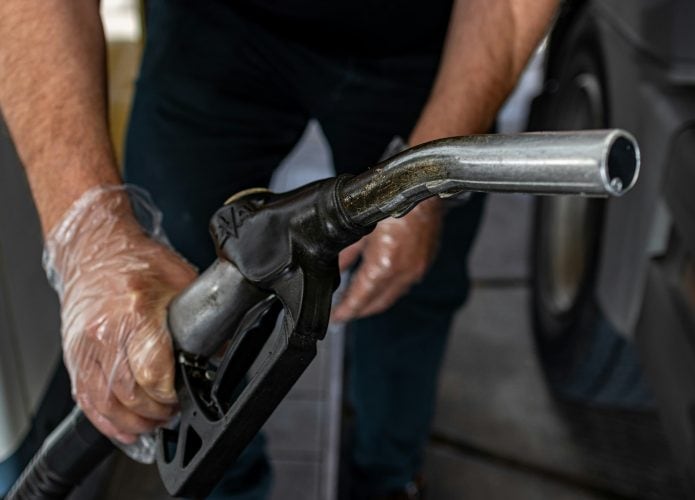 imagem mostra um frentista segurando o equipamento para abastecer o carro de uma pessoa no posto
