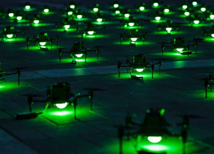 Drones enfileirados no chão com luzes verdes acesas