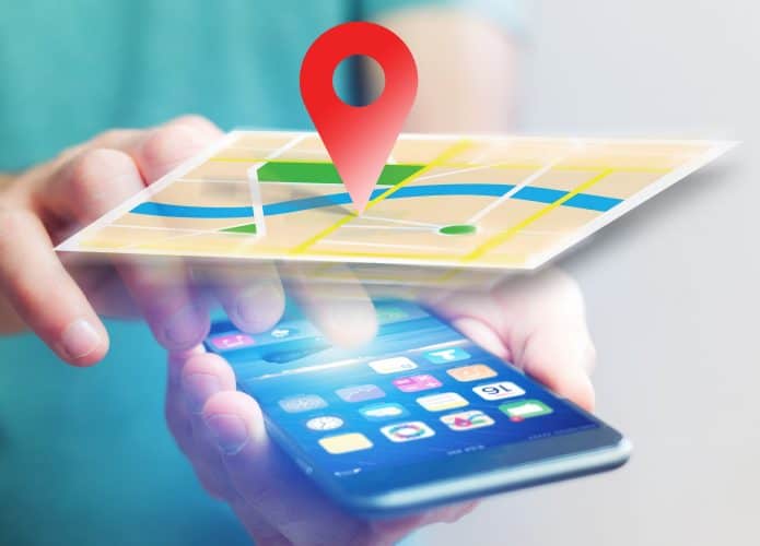 Montagem com holograma de mapa em cima de celular enquanto pessoa segura e toca no aparelho