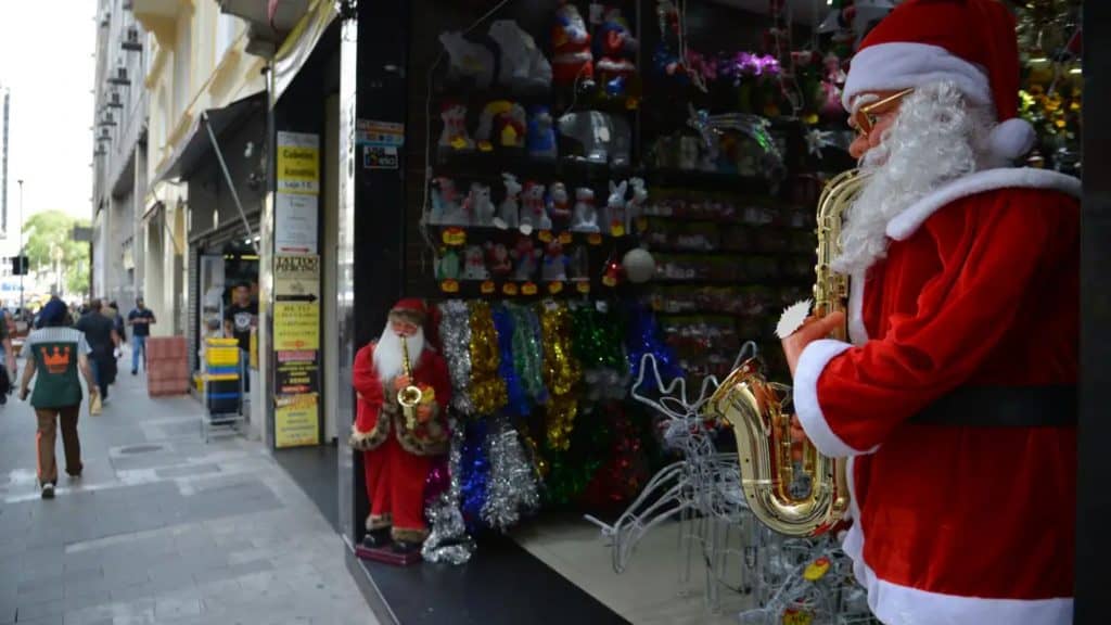 Bonecos de Papai Noel na entrada de uma loja no centro de uma cidade