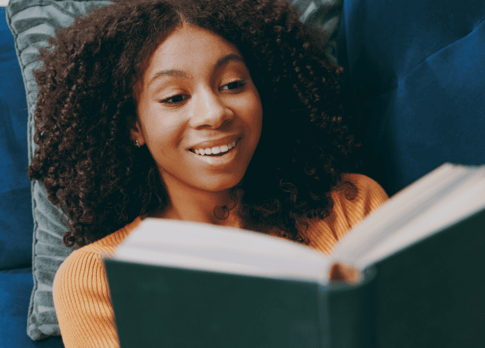Mulher lendo um livro enquanto está deitado em um sofá