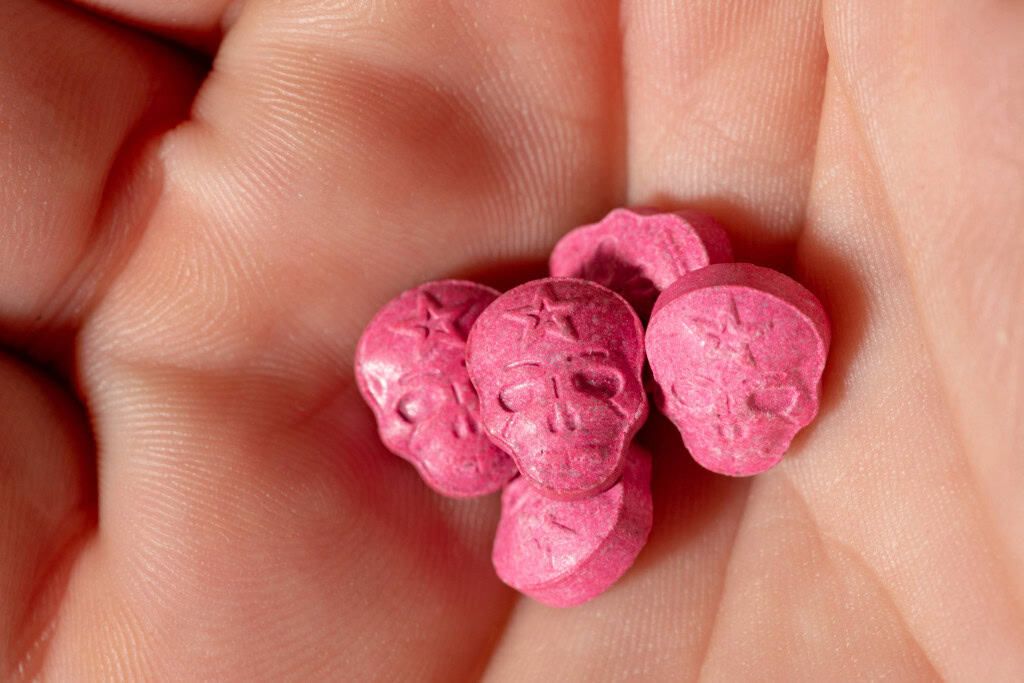 Pílula de MDMA/ecstasy na mão de um homem