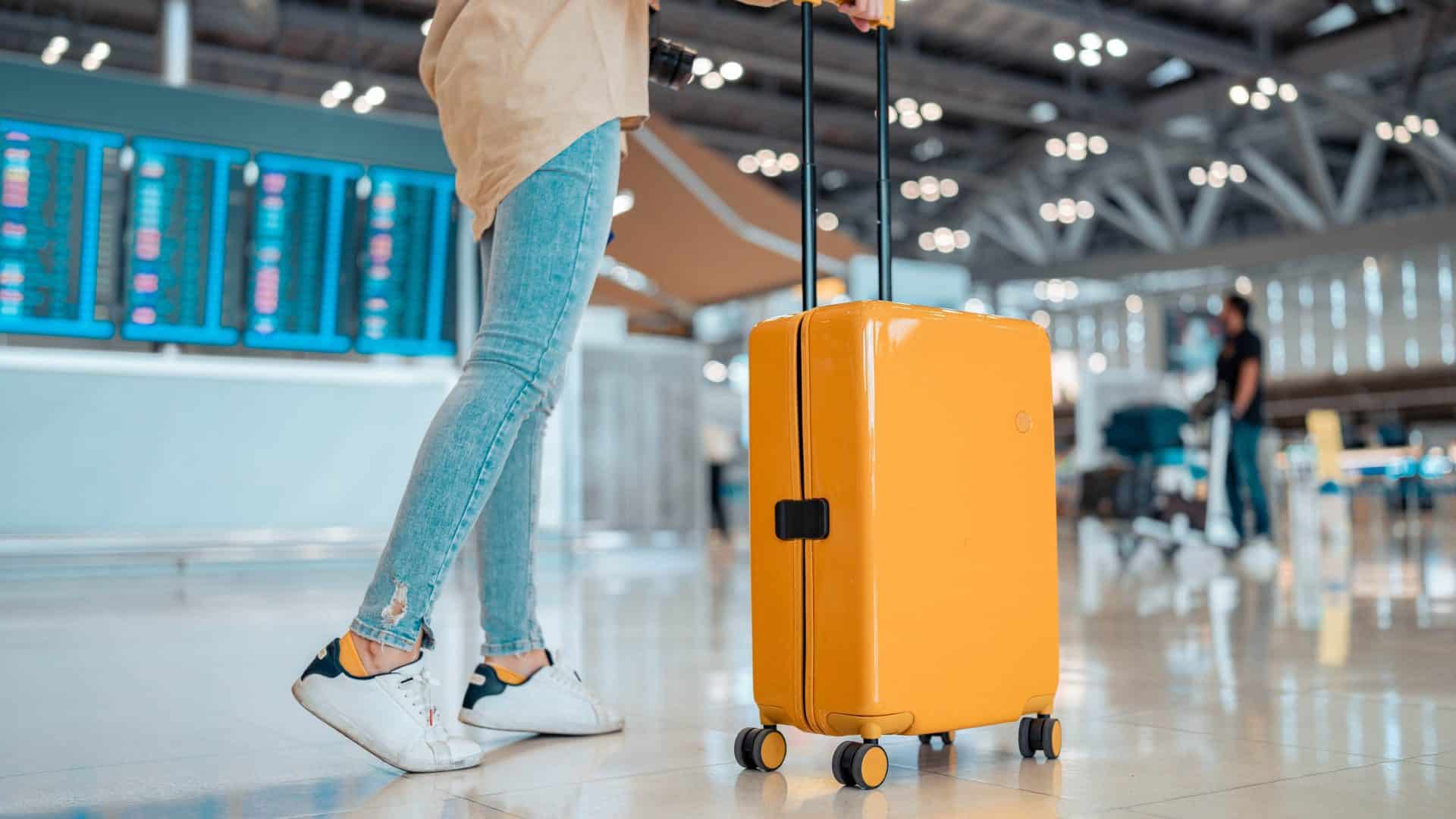 Jovem com mala em aeroporto; viagem