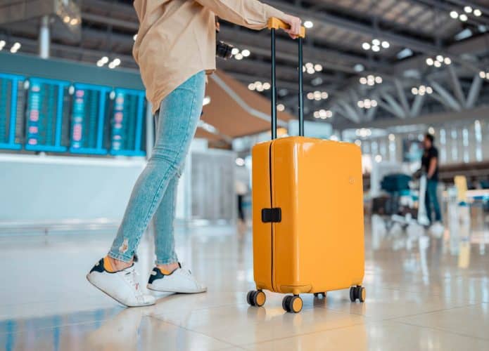 Jovem com mala em aeroporto; viagem