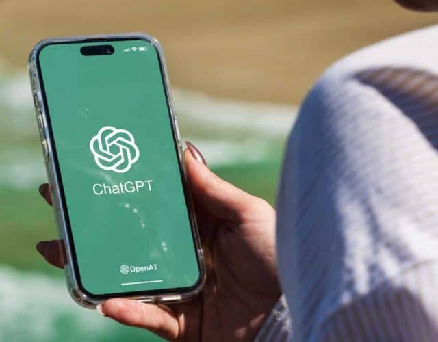 Pessoa segurando celular com logotipo do ChatGPT na tela