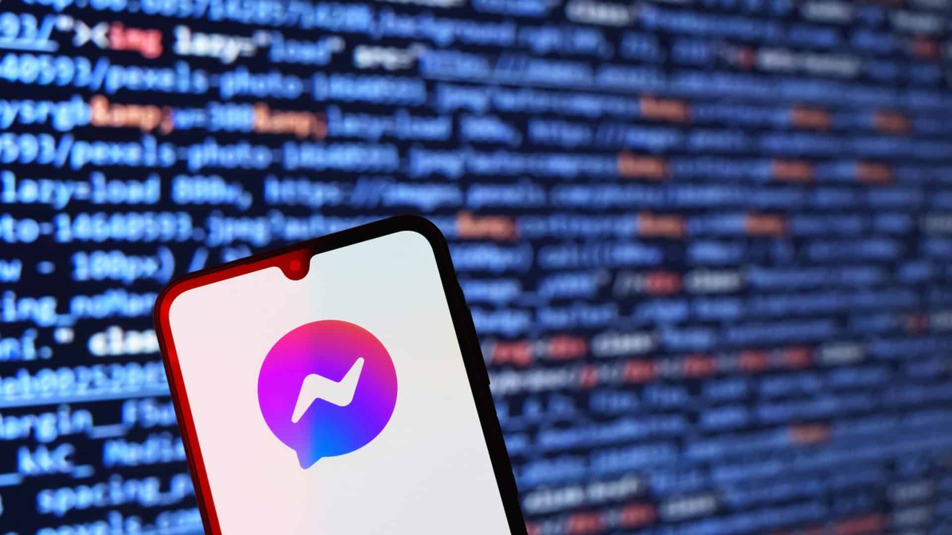Logo do Messenger em um smartphone; atrás, linhas de códigos de computador