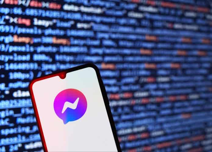 Logo do Messenger em um smartphone; atrás, linhas de códigos de computador