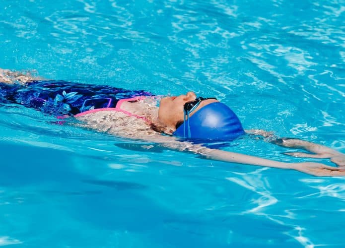 Mulher esportiva em óculos nadando de volta na piscina
