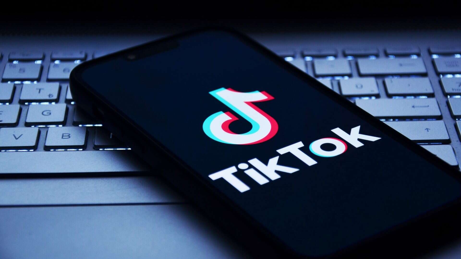 Logo do TikTok em um smartphone que está em cima de um notebook