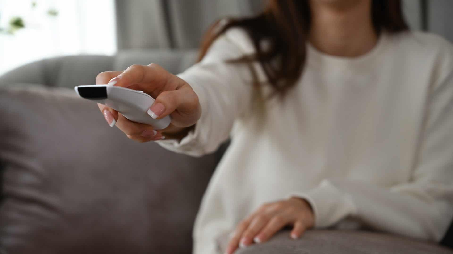 Pessoa com controle de smart tv na mão