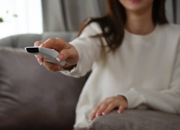 Pessoa com controle de smart tv na mão