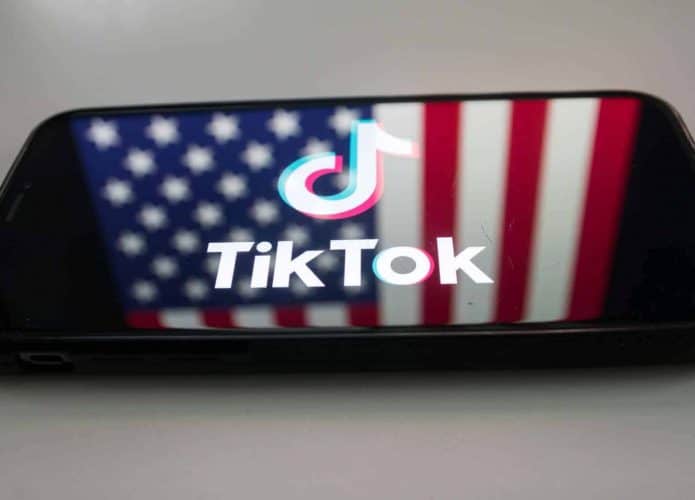 Logo do TikTok em um smartphone com a bandeira dos EUA de fundo
