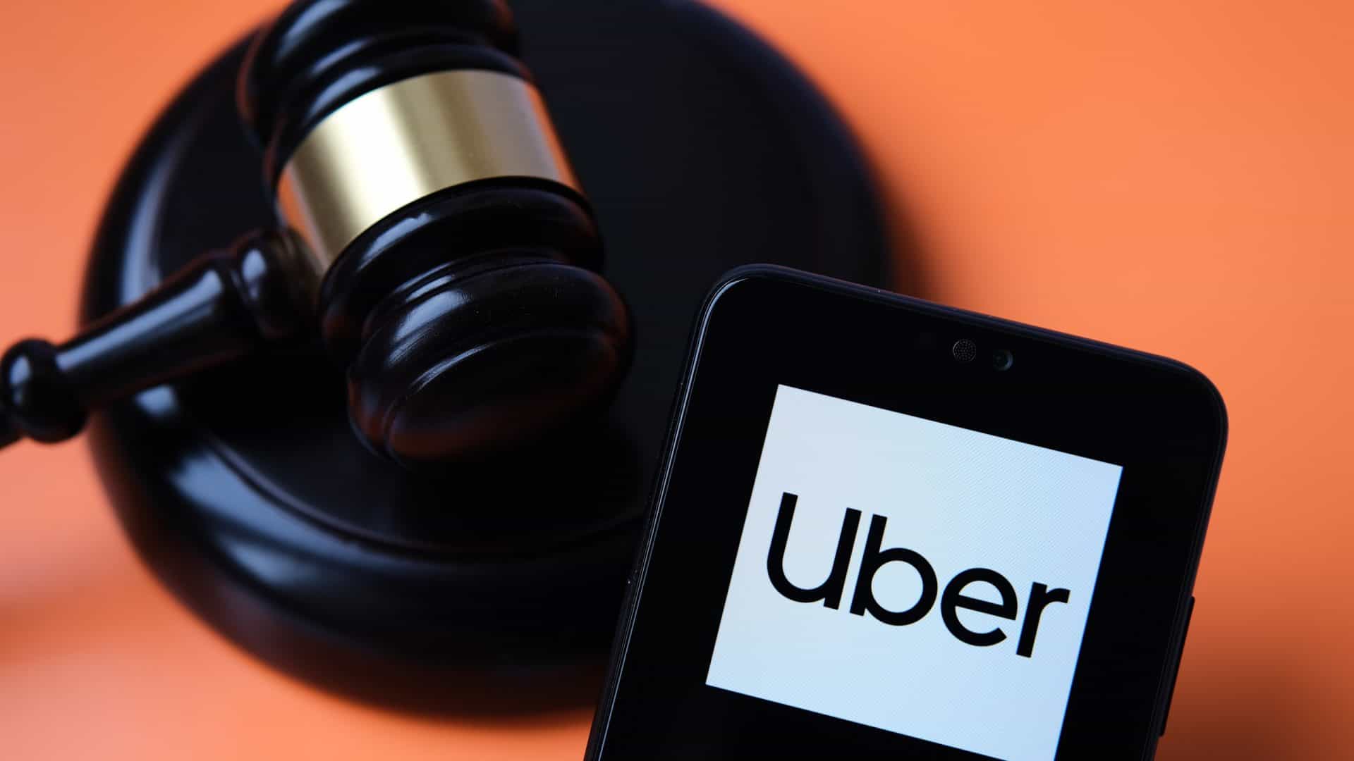 Logo da Uber em um smartphone ao lado de um martelo de juiz