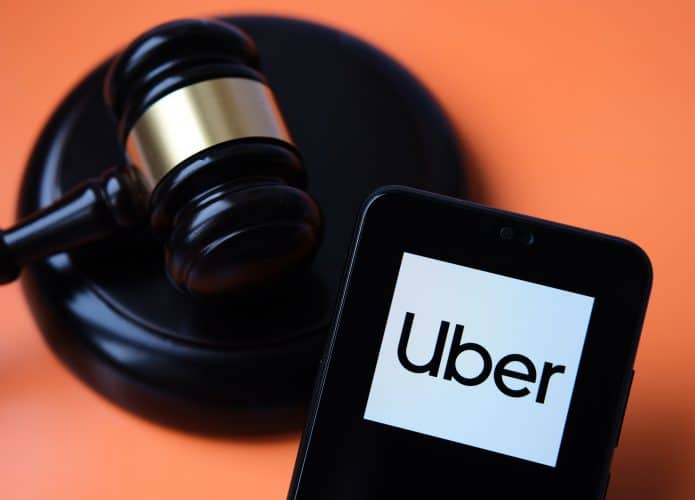 Logo da Uber em um smartphone ao lado de um martelo de juiz