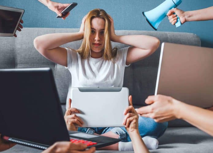Mulher com as mãos na cabeça, rodeada por dispositivos eletrônicos