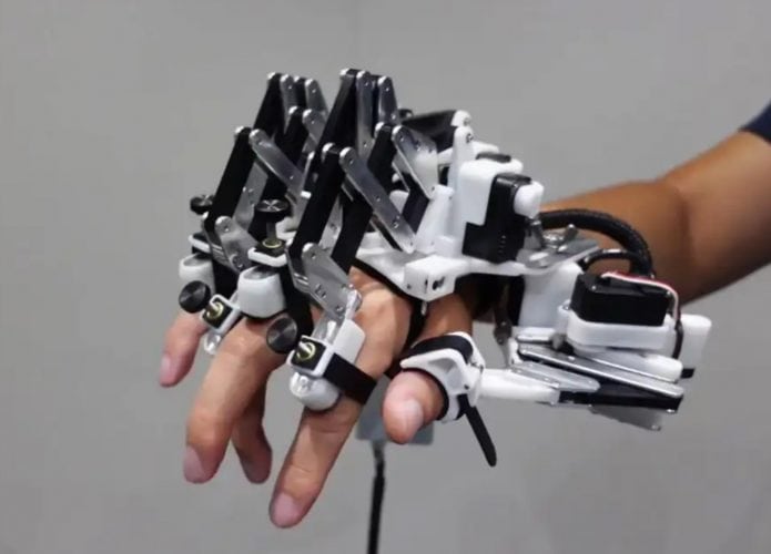 Mão robótica em cima de uma mão humana