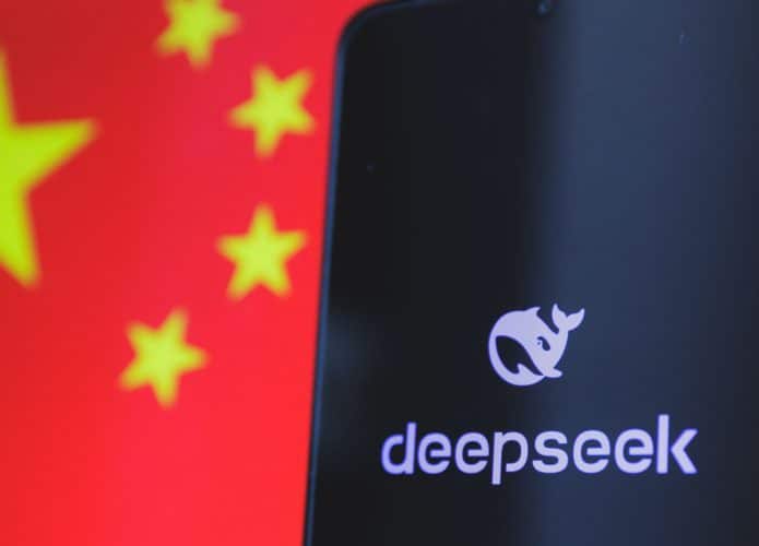 Celular com logotipo da DeepSeek na tela colocado na frente de tela exibindo bandeira da China