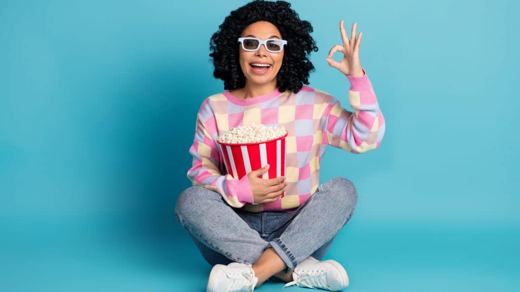 Foto corpo inteiro de atraente jovem mulher assistir filme ok vestido elegante rosa xadrez roupas isoladas no fundo cor azul