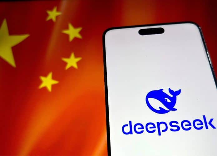 Celular com logotipo da DeepSeek na tela colocado na frente de monitor exibindo bandeira da China