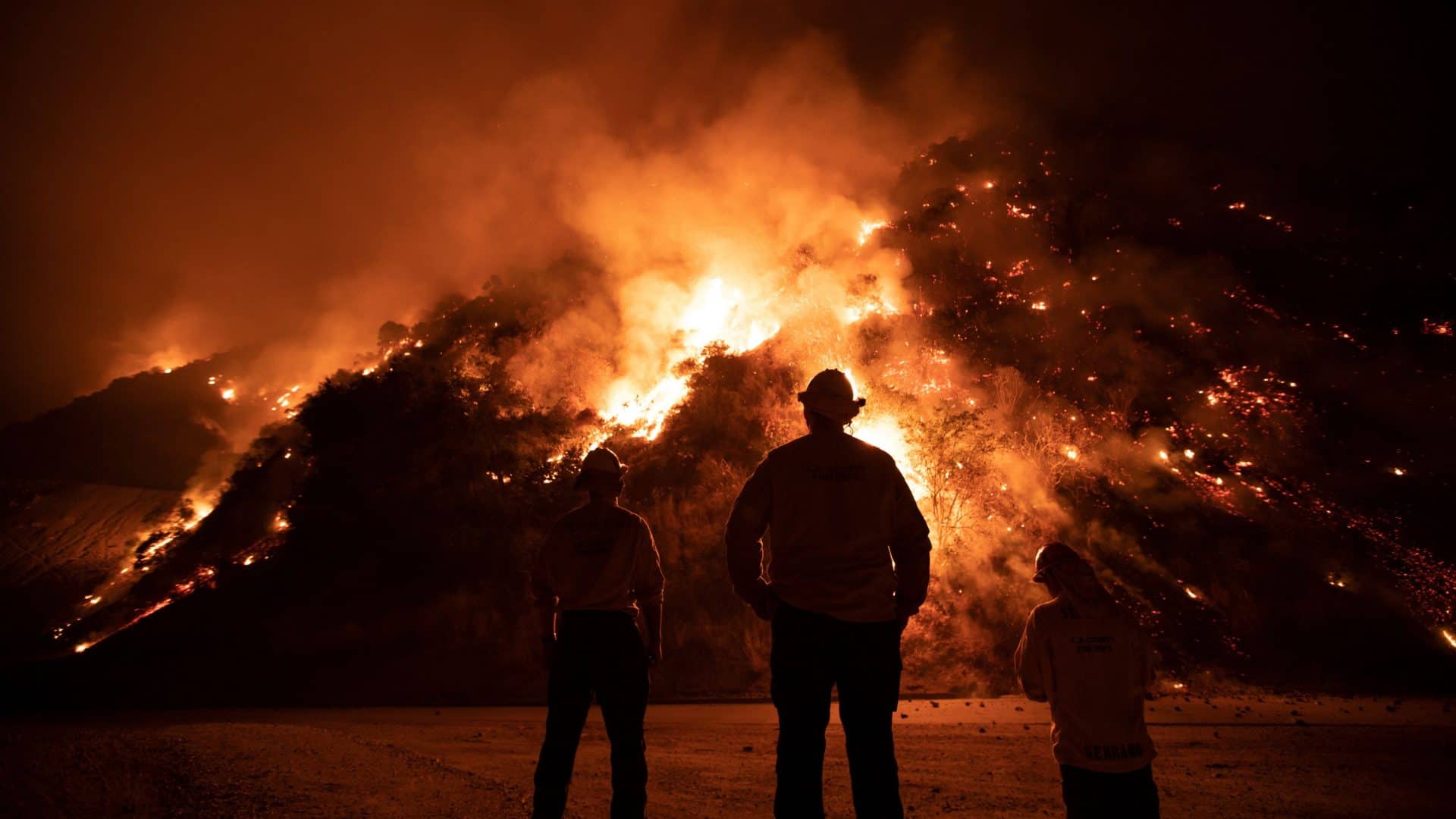 Bombeiros olhando para morros pegando fogo durante incêndios em Los Angeles em 2020