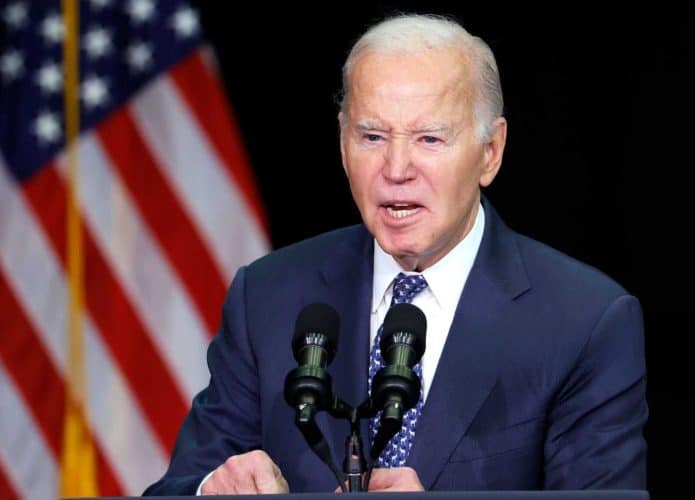 Joe Biden, na época presidente dos Estados Unidos, durante discurso em palanque com bandeira dos Estados Unidos no fundo