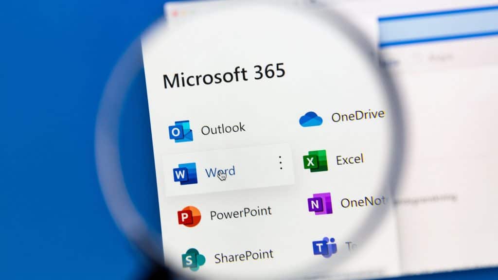 Pessoa segurando lupa sobre página com programas do Microsoft 365 (antigo Office) listados