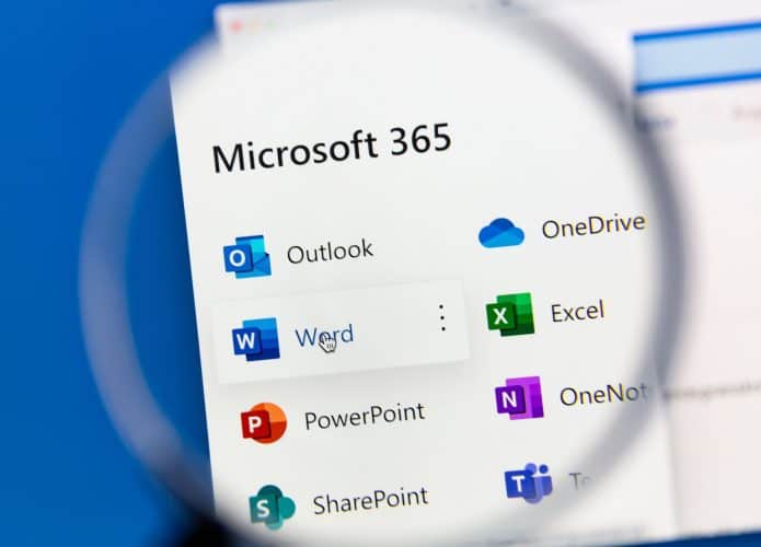 Pessoa segurando lupa sobre página com programas do Microsoft 365 (antigo Office) listados