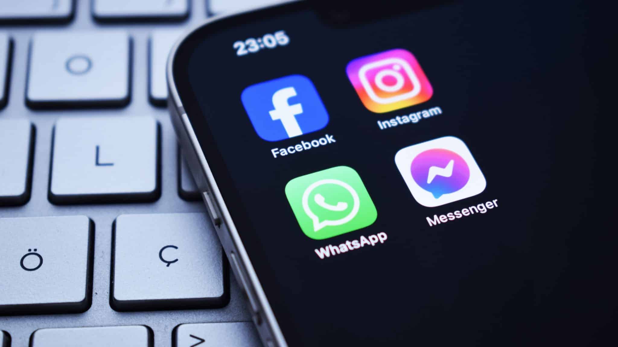 Ícones dos aplicativos do Facebook, Instagram, WhatsApp e Messenger, redes sociais da Meta, em tela inicial de um iPhone colocado sobre teclado de notebook