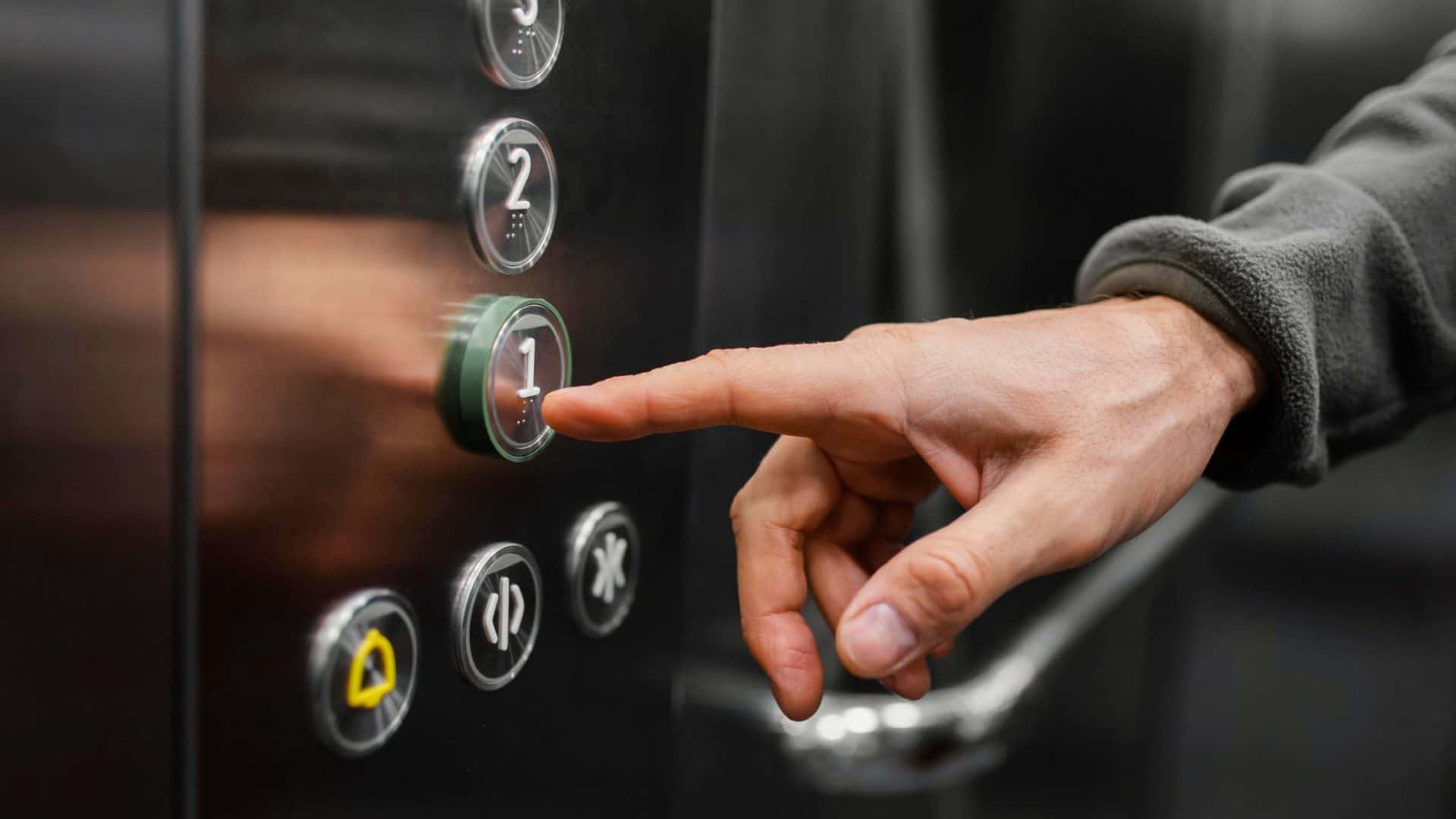 mão de homem apertando botões do elevador