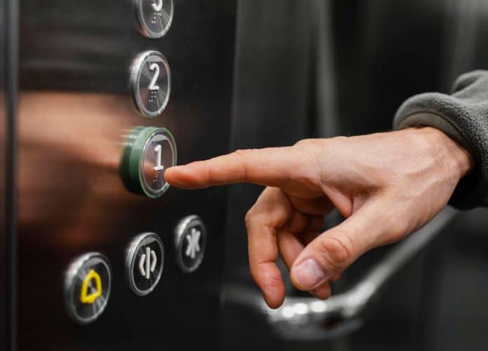 mão de homem apertando botões do elevador