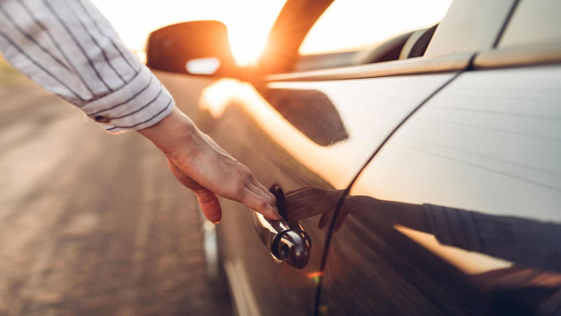 Imagem ilustrativa de mão em maçaneta de carro, sobre levar choque na porta do carro