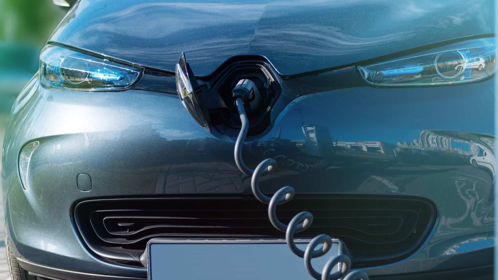 Um carro elétrico moderno conectado a uma estação de carregamento, com o cabo de recarga inserido na lateral do veículo.