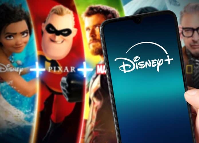 Logo do Disney+ em um smartphone; ao fundo, algumas das atrações oferecidas pelo streaming