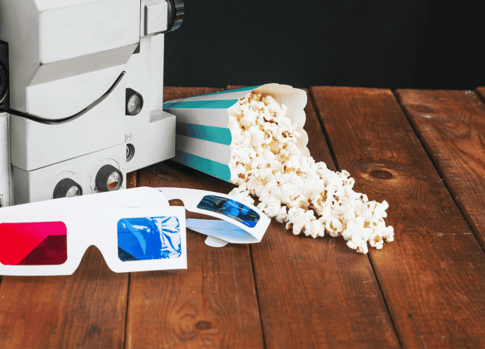 Pipoca derramada e óculos 3D perto do projetor