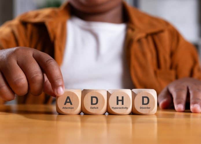 Blocos com letras enfileirados em uma mesa à frente de uma criança