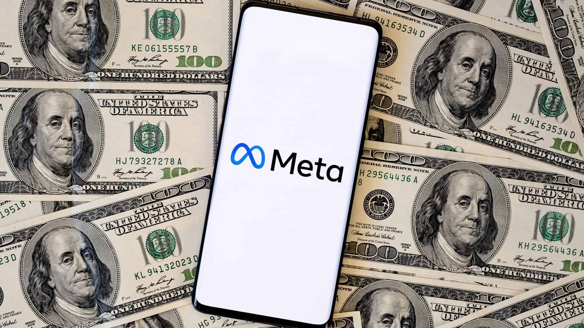 Logo da Meta em um smartphone, que está em cima de várias notas de dólares dos Estados Unidos