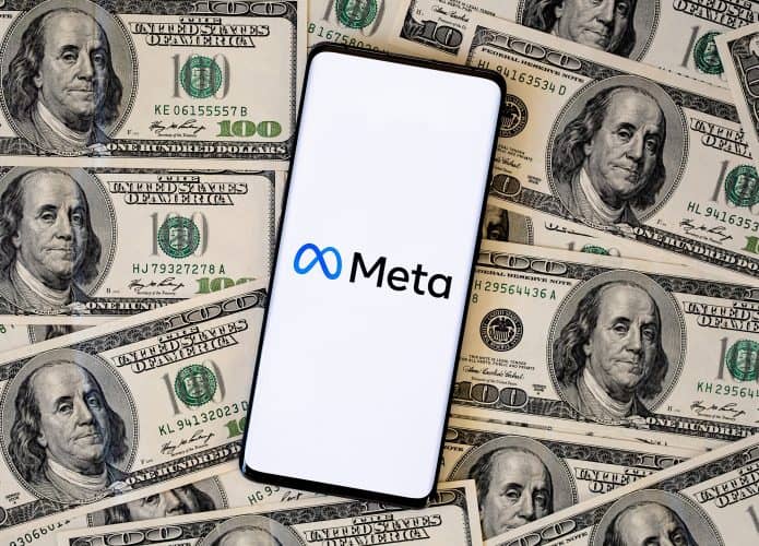 Logo da Meta em um smartphone, que está em cima de várias notas de dólares dos Estados Unidos