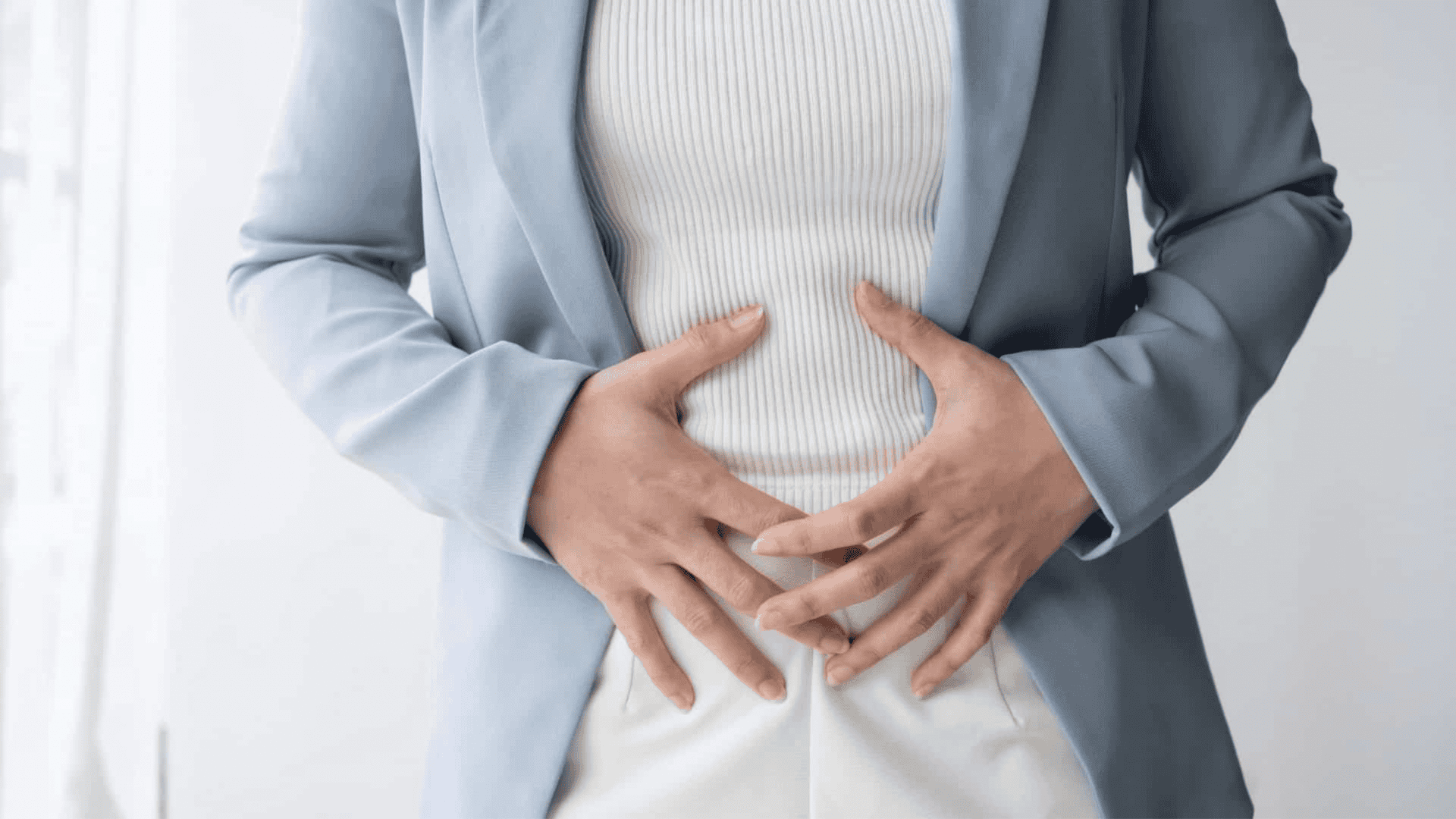 Mulher com as mãos na barriga devido à dor