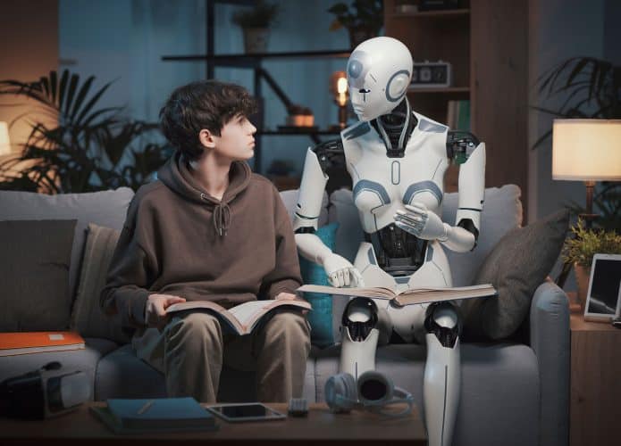 Robo sentado ao lado de um garoto, em um sofá e com um livro em suas pernas. Eles estão se olhando e o robô parece estar explicando algo ao garoto